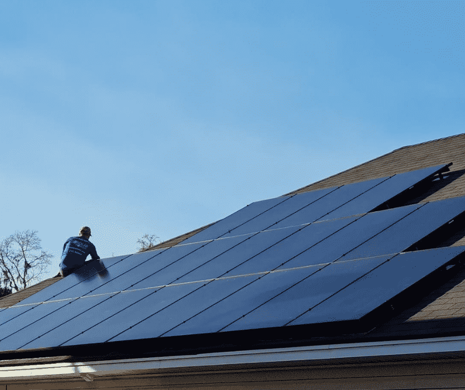 worker installing solar panels on roof