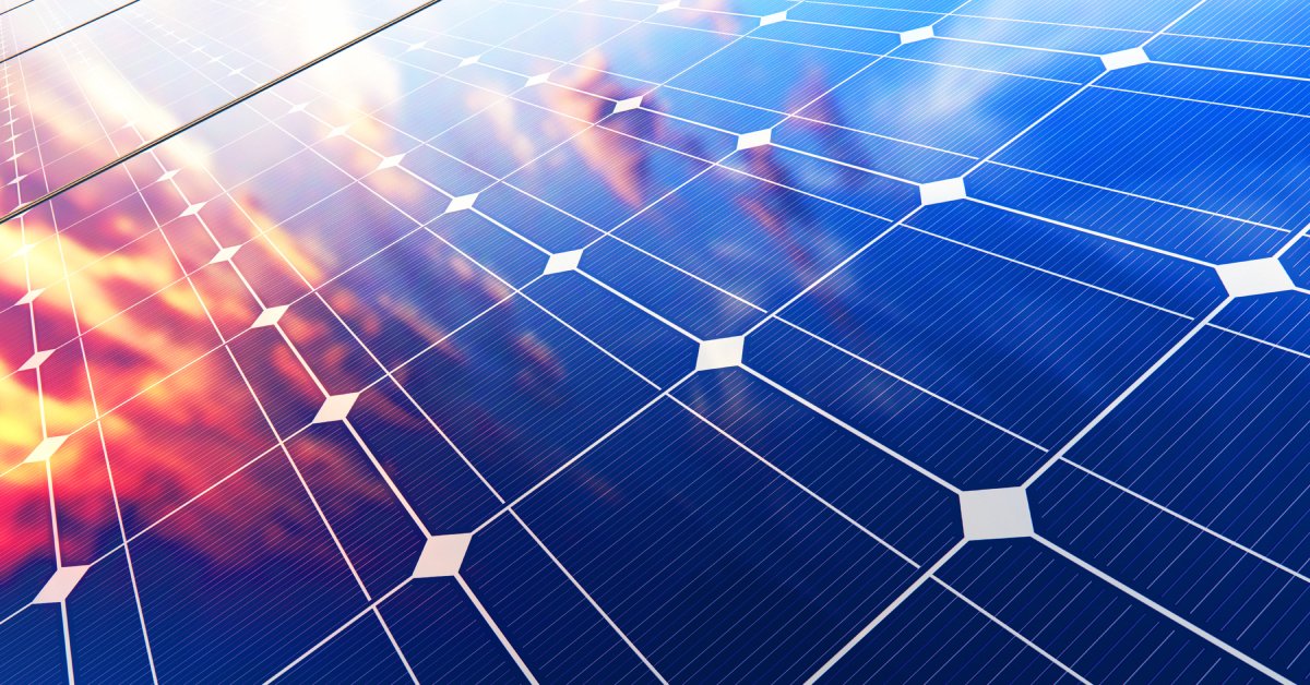 Close-up of multiple solar panels side by side with blue sensors and white lines reflecting the sun during sunset.