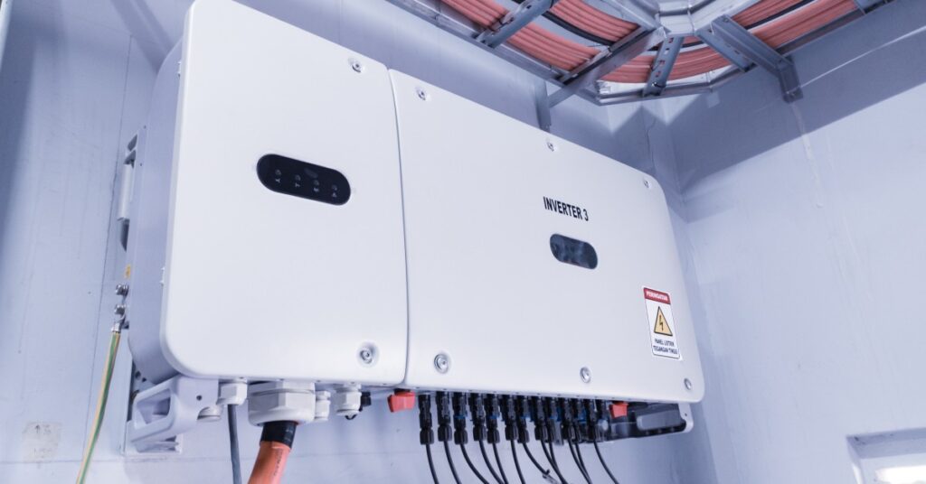 Tesla Megapack Battery Specifications and Capacity Details 5 A large white battery with multiple cables plugged in, placed on a white wall with multiple red tubes running on top.