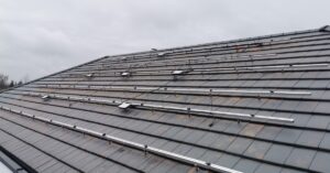 FAQ 4 A roof covered in small shingles, with a large metal structure spreading across with small microinverters attached.