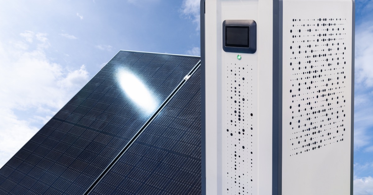 Tesla Solar Powerwall Operating Modes Explained 2 A tall white box with a small digital screen next to a standing solar panel with multiple cells under the sun.