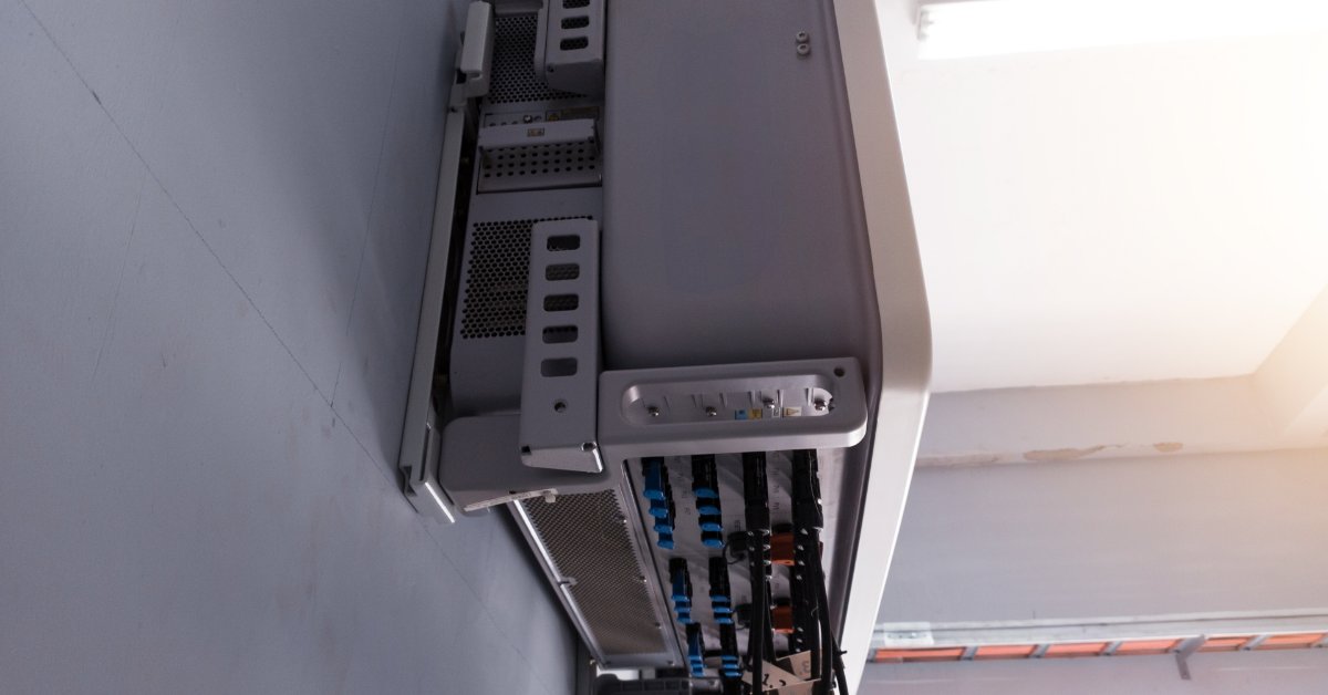Off-Grid Capabilities of the Tesla Powerwall 1 A view of the underside of a large white box attached to a wall with multiple orange and black cables attached.