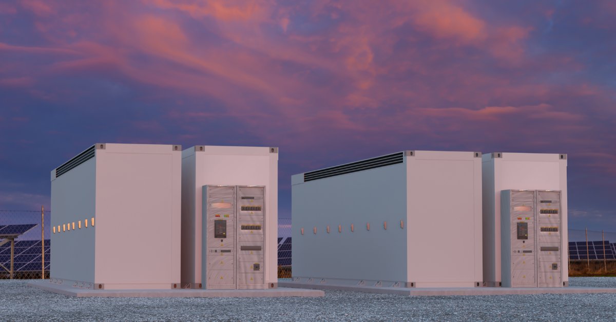 Megapack Installation and Site Requirements 2 Two large white containers with control panels on the side placed on a thin concrete slab outdoors surrounded by gravel.