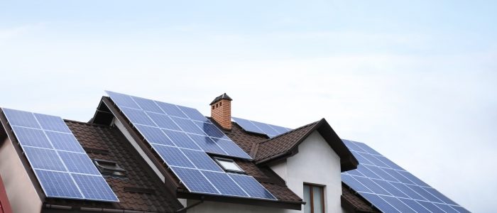 A close-up of the roof of a large two-story home with multiple rows of solar panels covering the entire surface.