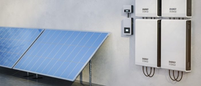 Four white rectangular boxes placed on a wall next to each other, with two large solar panels on the side.