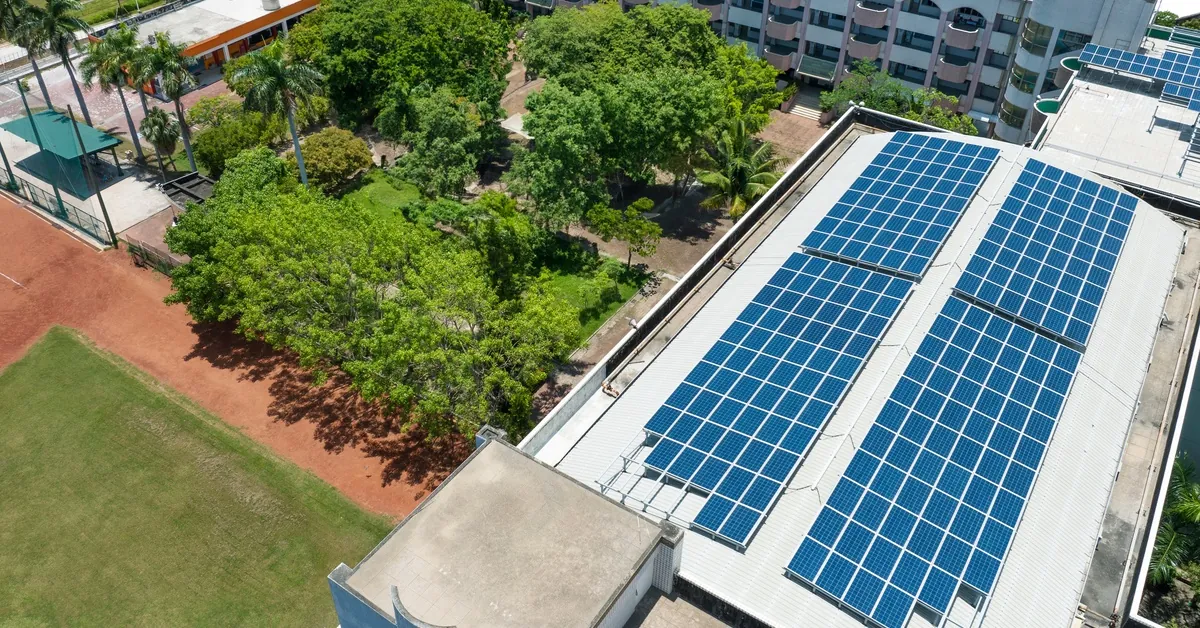 How Schools Are Benefiting From Commercial Solar Power 2 Aerial view of two four-story buildings with multiple solar panel rows on the roof and a center courtyard with trees.