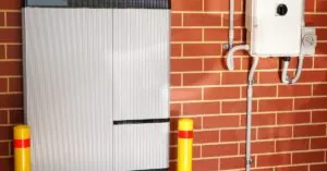 FAQ 4 Large white solar battery mounted on a brick wall next to a small converter with multiple cables attached.