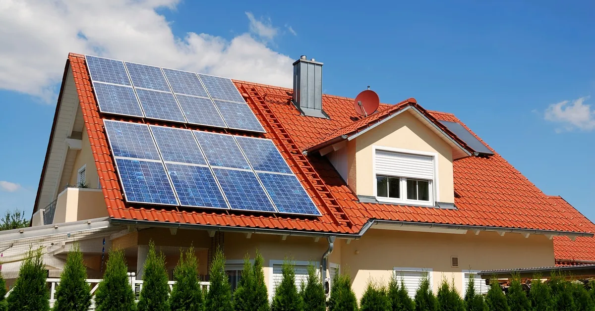 Learn 3 Two-story home with a large angled roof covered in brown shingles with multiple rows of solar panels on the left.