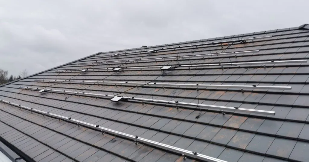 Microinverters vs. String Inverters for Home Solar Power 1 A roof covered in small shingles, with a large metal structure spreading across with small microinverters attached.
