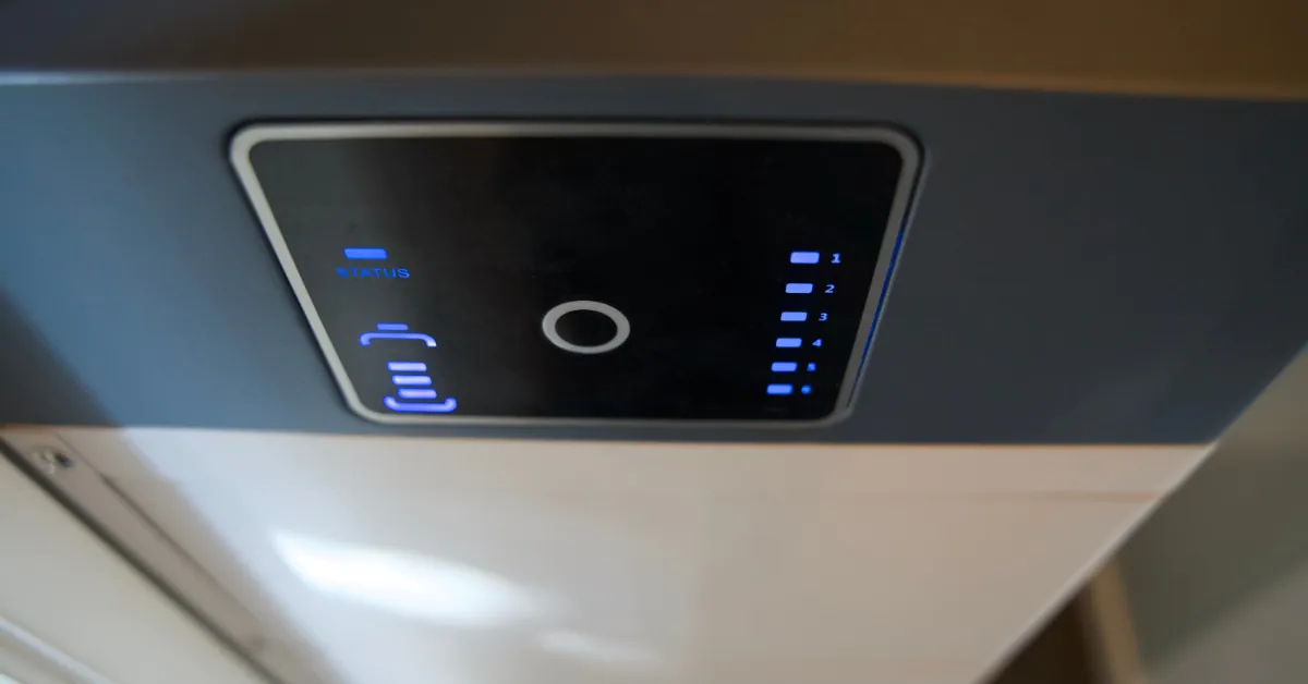 A close-up of a digital screen with a small button in the middle and displaying digital numbers on a large metal box.