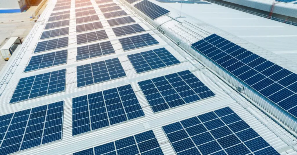 Scaling Solar for Manufacturing Facilities 5 An aerial view of the roof of a large white building covered in multiple rows of solar panels on a sunny day.